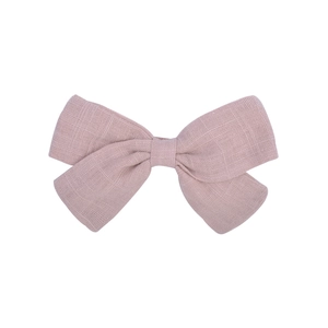 Detail of a dusty rose pink cotton linen bow hair clip with textured fabric weave