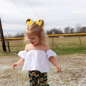 Photo en extérieur d'une fille portant un pantalon à fleurs de tournesol et un haut blanc