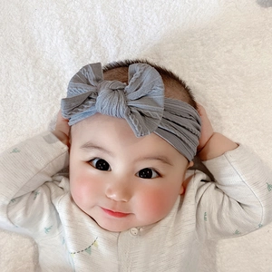 Soft nylon baby headband with a large grey cable knit bow on white plush background