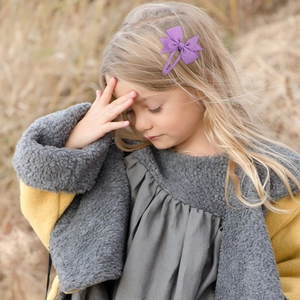 Girl wearing purple grosgrain bow hair clip for toddlers with comfortable BB clip design