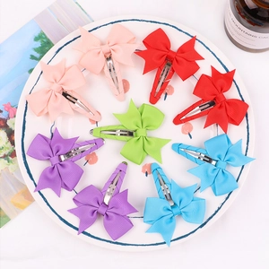 Nine-piece set of colorful ribbon bow hair clips for girls displayed on a white plate