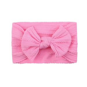 Pink soft nylon headband for babies featuring a large knitted bow and cable pattern