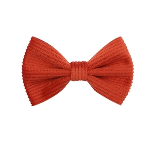 Close-up detail of orange corduroy bow hair clip showing textured fabric material