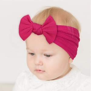 Close-up of soft rose pink nylon headband with a large bow and ribbed texture for infants