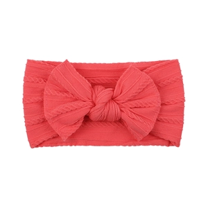 Detailed macro view of coral red baby headband with jacquard knit and soft bow accent