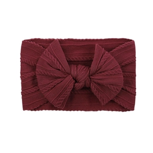 Detailed close-up of dark burgundy nylon knit headband with large bow for baby girls