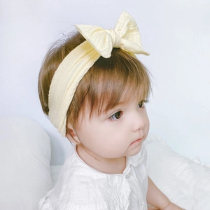Elastic baby nylon headband with jacquard bow in soft yellow on an infant model