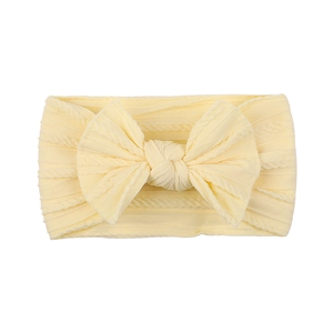 Detail view of baby cable knit headband with large bow in soft pale yellow nylon fabric
