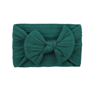 Detail of dark green cable knit nylon baby headband with a large soft bow decoration
