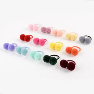 Flat lay of multiple colorful plush ball elastic hair ties on a plain white background