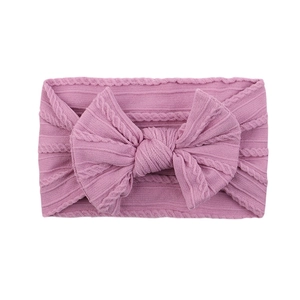 Macro detail of dusty pink ribbed baby headband featuring a large knitted bow design