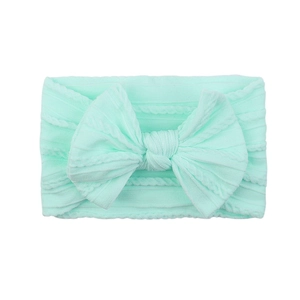 Detail of mint green baby nylon headband showing soft ribbed texture and large bow knot