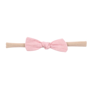 Close-up of pink linen bow on a beige elastic nylon headband for baby girls