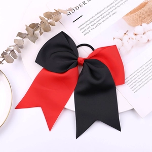Detailed close-up of large red and black ribbon bow hair tie with grosgrain texture