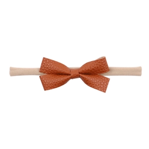 Detailed macro view of caramel leather bow on soft nylon infant elastic headband