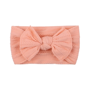 Detailed macro shot of soft nylon baby headband with textured knit bow in coral pink