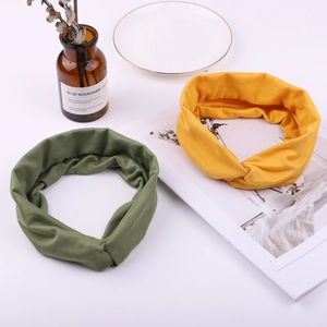 Detailed view of criss-cross knot headbands in olive green and mustard yellow soft cotton fabric