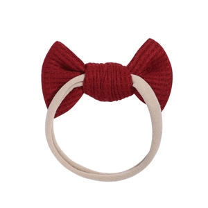 Knotted baby headband with dark red waffle knit bow on stretchy beige nylon band