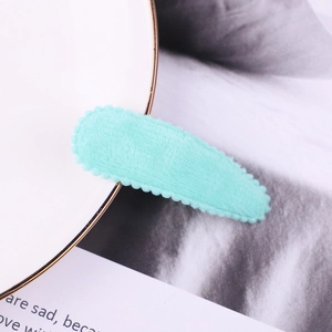 Detail of mint green plush hair clip with scalloped edges on a ceramic plate