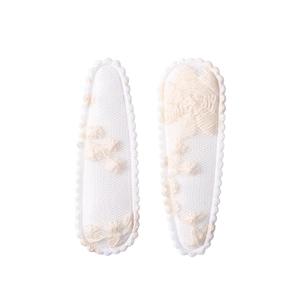 Close-up of white floral embroidery and scalloped edges on fabric snap hair clips