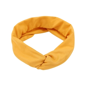 Detail view of ginger yellow twisted knot headband in soft knitted cotton fabric