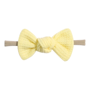 Detailed close-up of pale yellow waffle fabric bow and soft elastic band for baby headbands