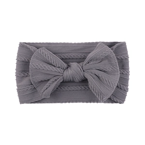 Detail of soft ribbed nylon baby headband featuring a large knitted bow in dark grey