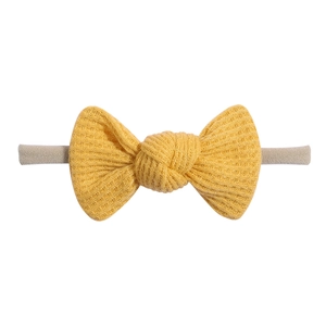 Detailed macro view of yellow waffle knit baby headband with textured bow design