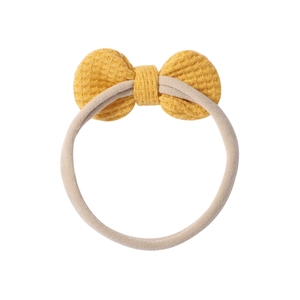 Detailed view of yellow waffle knit bow headband with highly elastic nylon band for infants