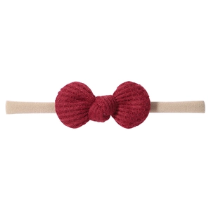 Close-up of soft waffle knit dark red bow and nude elastic nylon headband for babies