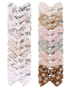 Flat lay of 12 floral fabric bow hair clips featuring embroidery and gingham patterns