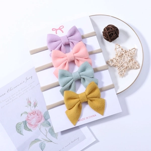 Detail of four soft nylon baby headbands with colorful fabric bows on a display card