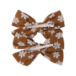 Detail view of brown fabric hair bows with daisy embroidery and metal alligator clips