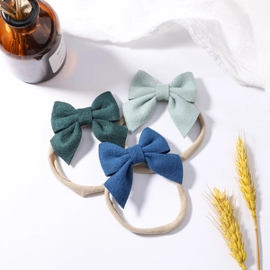 Three-piece set of soft nylon baby headbands with colorful bows in green and blue