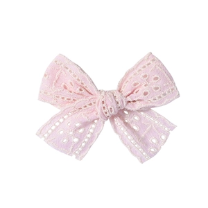 Détail d'une pince à cheveux avec nœud en dentelle rose et broderie ajourée élégante