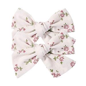 Floral print bow hair clips with pastel purple blossoms and green leaves on white cotton