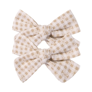 Detail of floral checkered fabric bow clips featuring small daisies and linen texture