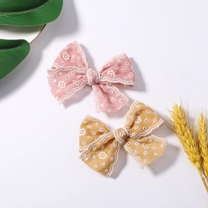 Detail of pink and mustard yellow fabric bow hair clips with delicate flower embroidery