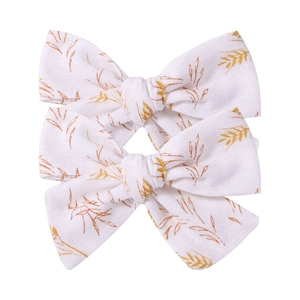 Detail of three floral bow hair clips featuring yellow wheat patterns on linen fabric