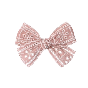 Détail du nœud à cheveux en dentelle rose avec broderie florale et bords festonnés délicats