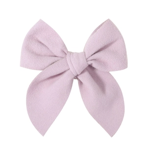 Macro detail of lavender satin fabric bow hairclip showing texture and central knot