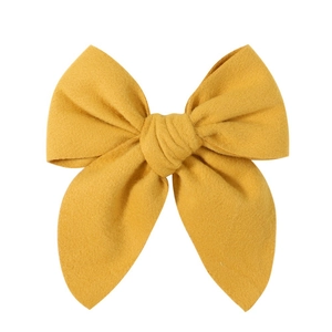 Detail view of ginger yellow woolen bow hair clip with textured fabric on white background