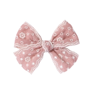 Détails de broderie florale et dentelle ajourée sur un nœud papillon rose