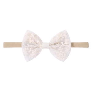 Détail du nœud papillon en dentelle blanche sur un bandeau de bébé en nylon souple