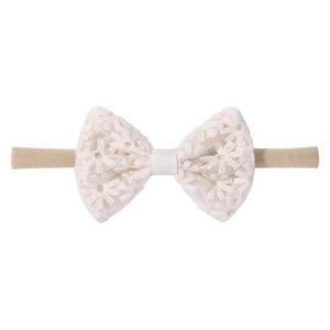 Détail d'un bandeau pour bébé avec nœud en dentelle blanche et broderie de marguerite