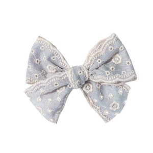 Détail de la broderie florale sur le nœud papillon bleu avec bords festonnés