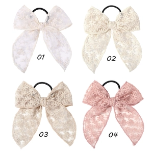 Detail of four embroidered lace bow hair ties with daisy patterns in multiple colors