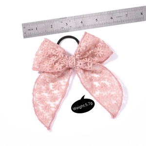 Pink lace bow hair tie with floral embroidery and ruler scale for size reference