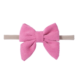 Dettaglio del fiocco in velluto a coste rosa e fascia elastica per neonati