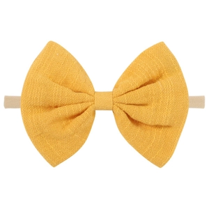 Detail of a bright yellow cotton bow headband with a pink elastic nylon strap for infants